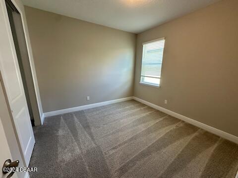 unfurnished room with dark carpet