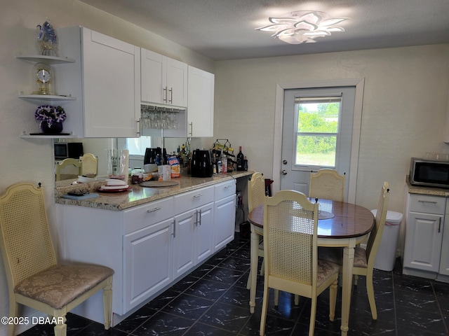 1956 Linda Ave, Ormond Beach, FL 32174 - kitchen featuring stainless steel microwave, open shelves, white cabinetry, and dark tile patterned flooring