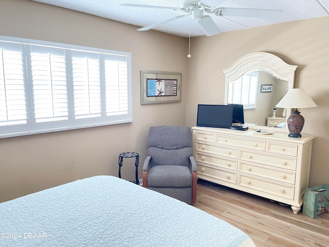 bedroom featuring light wood-type flooring, multiple windows, a textured ceiling, and ceiling fan