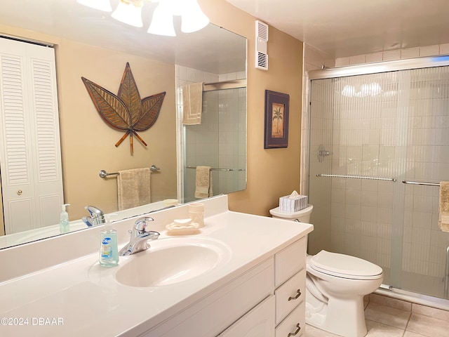 bathroom featuring toilet, vanity, tile patterned floors, and a shower with shower door