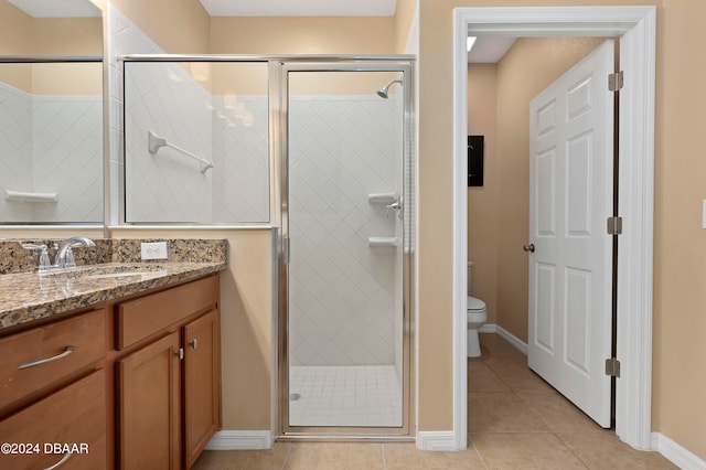 bathroom featuring tile patterned flooring, vanity, toilet, and a shower with door