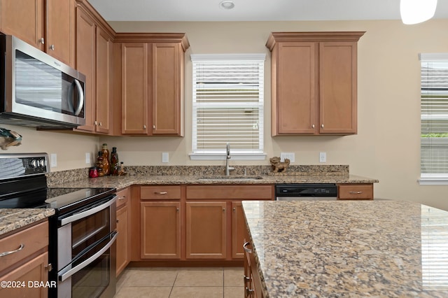 kitchen with stainless steel appliances, sink, light stone counters, and light tile patterned flooring