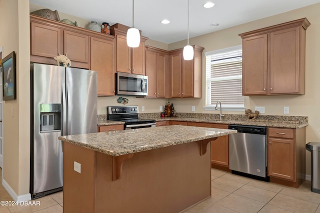 kitchen with light tile patterned flooring, appliances with stainless steel finishes, light stone countertops, a center island, and pendant lighting