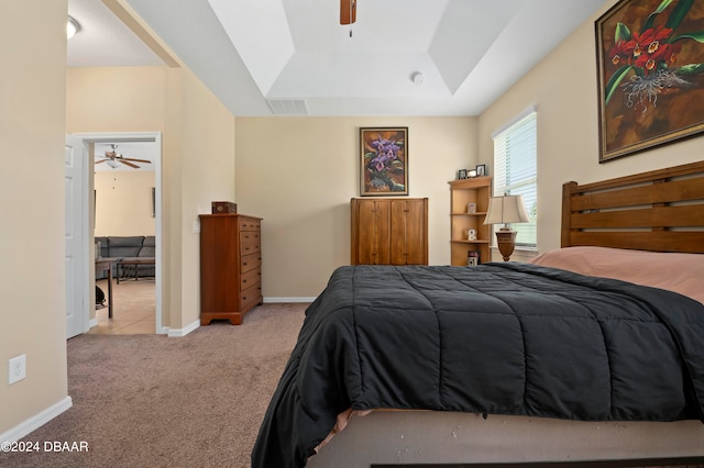 bedroom with ceiling fan, light carpet, and a raised ceiling