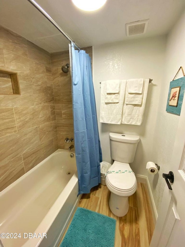 bathroom featuring hardwood / wood-style flooring, shower / tub combo with curtain, and toilet