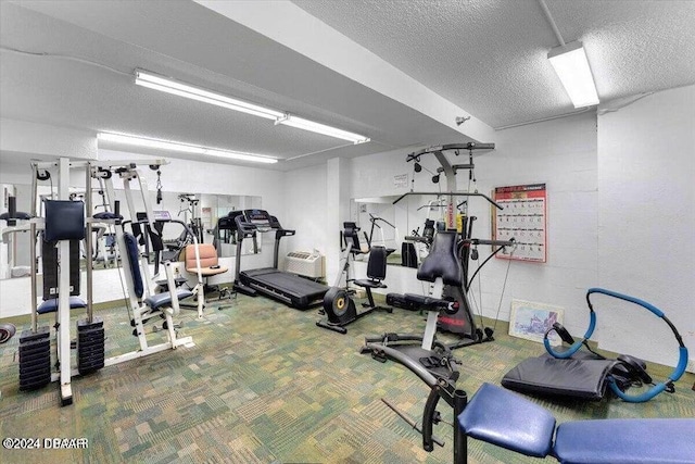 exercise room featuring carpet floors and a textured ceiling