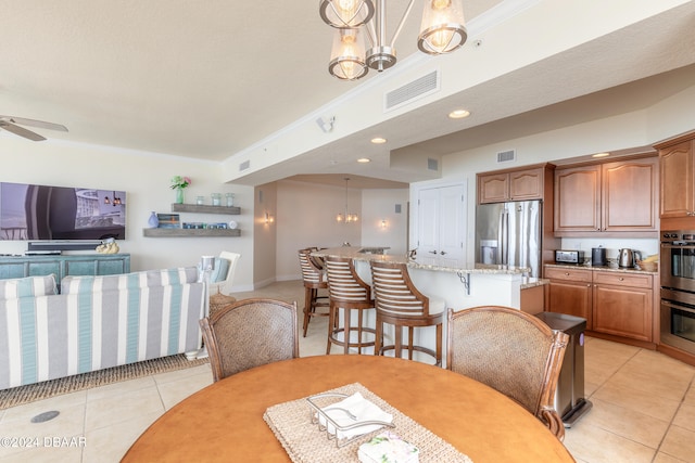 dining area featuring ceiling fan with notable chandelier, light tile patterned floors, and crown molding