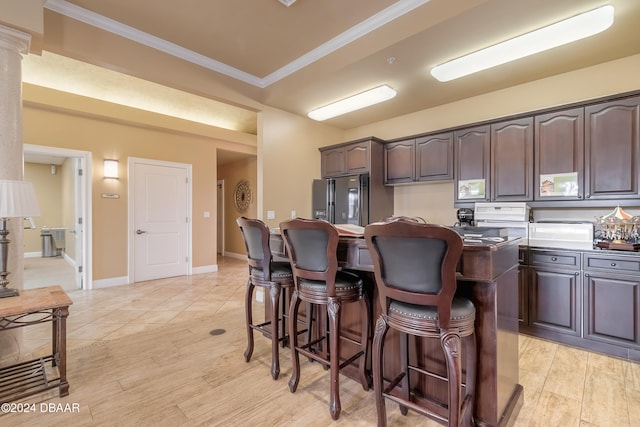 kitchen featuring dark brown cabinets, a kitchen bar, and ornamental molding