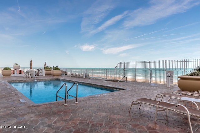 view of pool featuring a patio and a water view