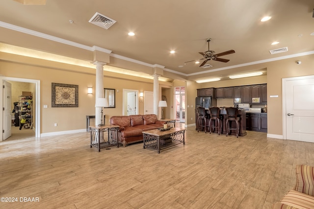 living room with ornate columns, light hardwood / wood-style floors, ornamental molding, and ceiling fan