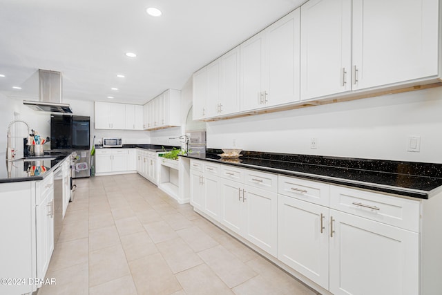 kitchen with light tile patterned flooring, dark stone countertops, white cabinetry, and extractor fan