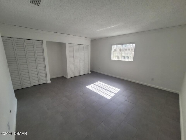 unfurnished bedroom featuring a textured ceiling and two closets