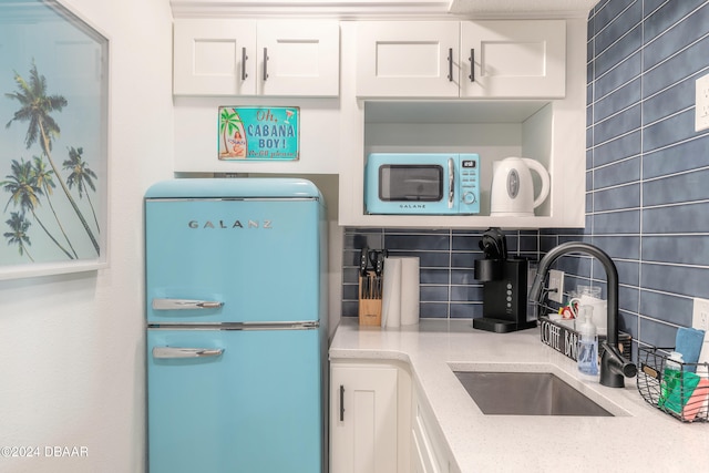 kitchen featuring white cabinets, refrigerator, sink, and backsplash