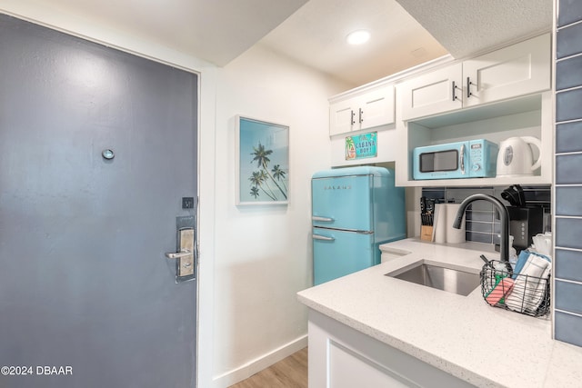 kitchen featuring refrigerator, white cabinetry, sink, and light hardwood / wood-style flooring