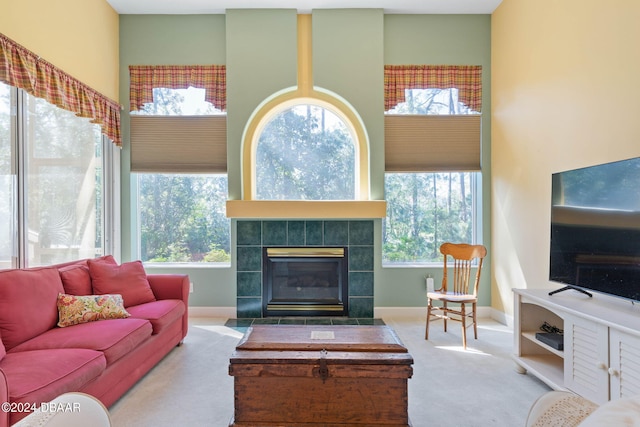 carpeted living room featuring a tiled fireplace and plenty of natural light