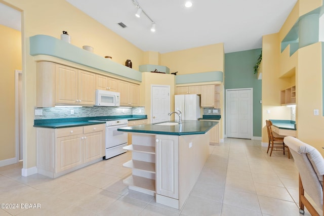 kitchen with sink, light tile patterned floors, white appliances, a towering ceiling, and a kitchen island with sink