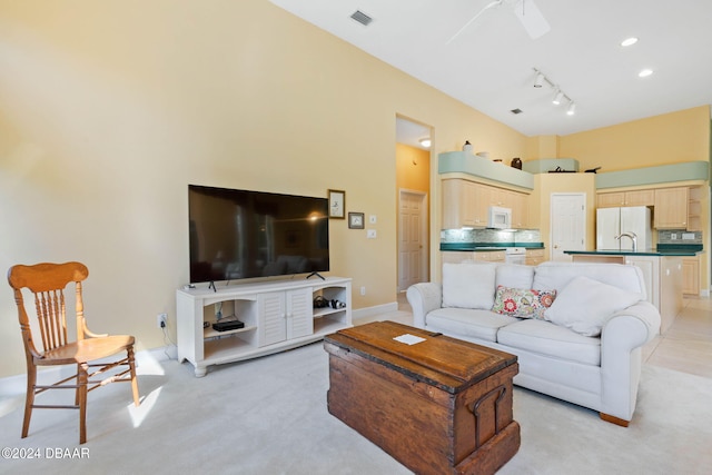 carpeted living room with track lighting, ceiling fan, and sink