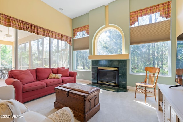 living room featuring light colored carpet, a healthy amount of sunlight, and a tile fireplace