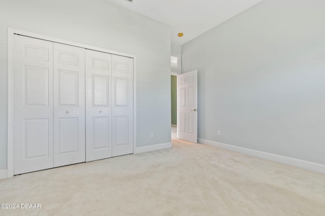 unfurnished bedroom with a closet and light colored carpet