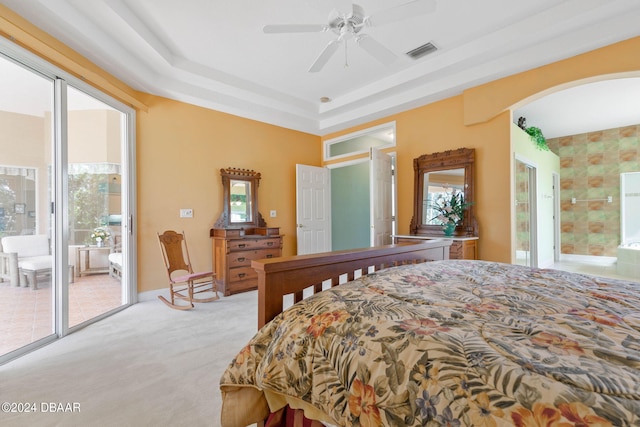 carpeted bedroom featuring a tray ceiling, multiple windows, ceiling fan, and access to exterior