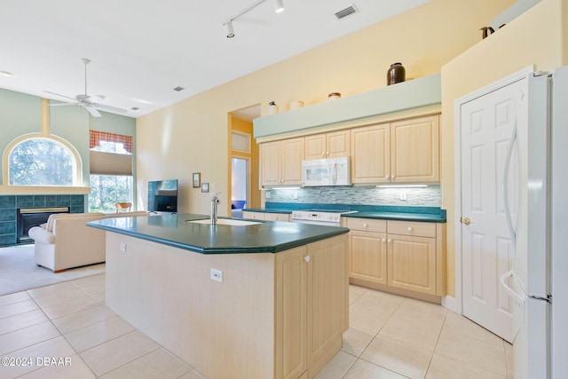 kitchen featuring white appliances, sink, light tile patterned floors, and a fireplace