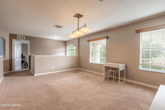 carpeted spare room featuring a textured ceiling and plenty of natural light