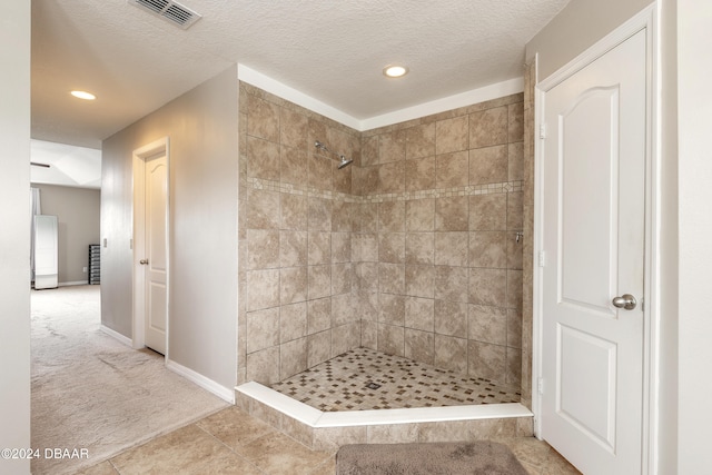 bathroom featuring tile patterned flooring, a textured ceiling, and a tile shower