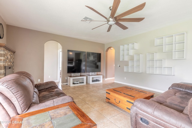 tiled living room featuring a fireplace and ceiling fan