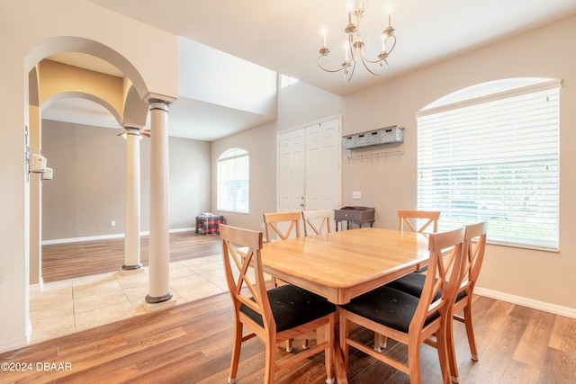 dining space with light hardwood / wood-style floors, a healthy amount of sunlight, decorative columns, and an inviting chandelier