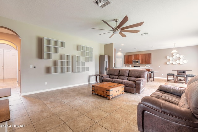 living room with a textured ceiling, ceiling fan with notable chandelier, and light tile patterned flooring