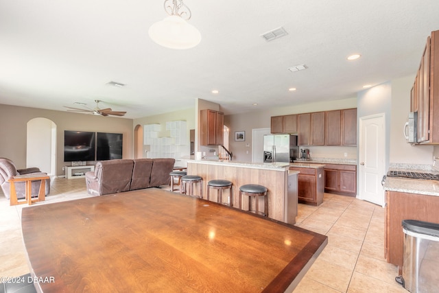 kitchen with a center island with sink, appliances with stainless steel finishes, hanging light fixtures, a breakfast bar, and ceiling fan