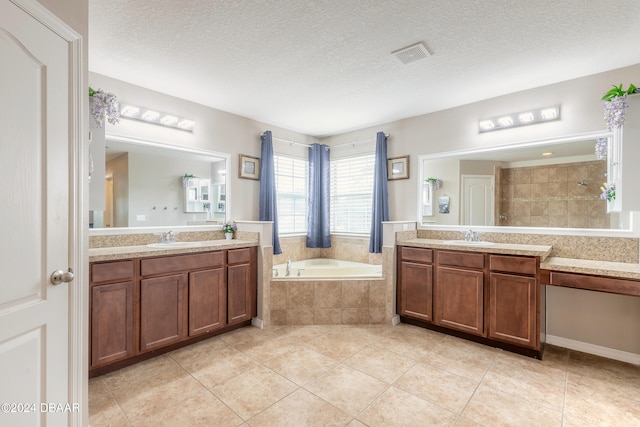 bathroom with tiled bath, tile patterned flooring, vanity, and a textured ceiling