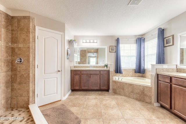 bathroom featuring tile patterned flooring, shower with separate bathtub, vanity, and a textured ceiling