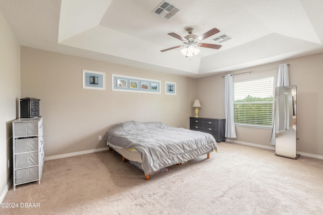 carpeted bedroom featuring ceiling fan and a raised ceiling