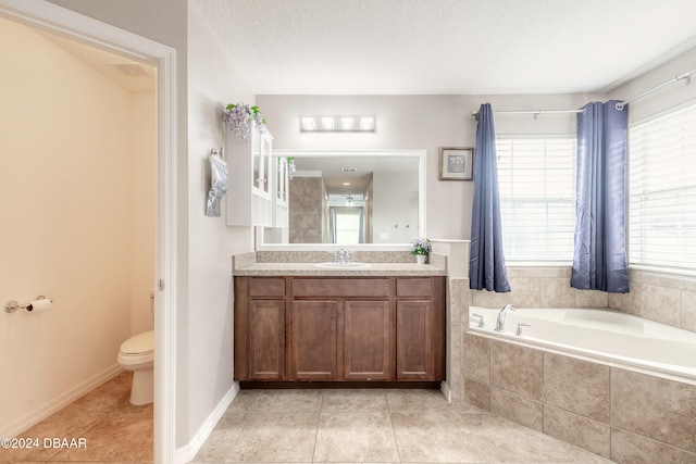 bathroom with toilet, tiled bath, a textured ceiling, and a healthy amount of sunlight