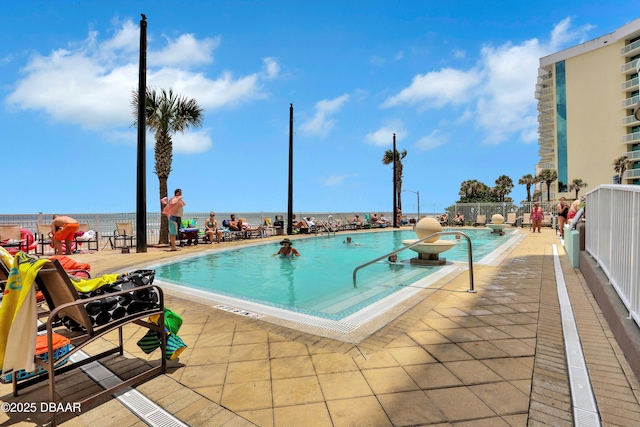 view of swimming pool featuring a patio and a water view