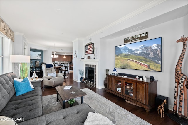 living room with a tile fireplace, ornamental molding, and dark wood-type flooring