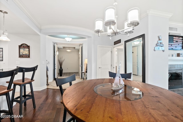 dining space featuring ornamental molding, a chandelier, and dark hardwood / wood-style flooring