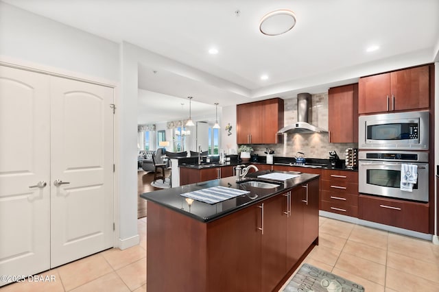 kitchen featuring wall chimney range hood, sink, a kitchen island with sink, stainless steel appliances, and light tile patterned flooring