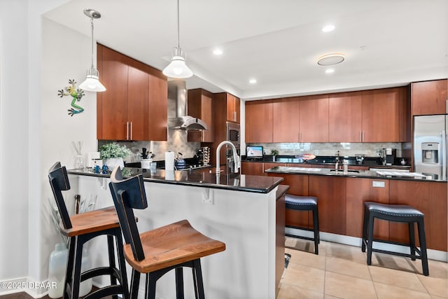 kitchen with wall chimney exhaust hood, a kitchen breakfast bar, kitchen peninsula, pendant lighting, and decorative backsplash