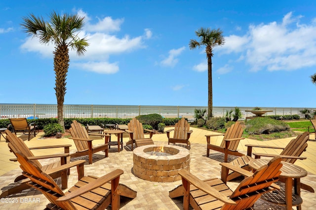 view of patio / terrace featuring a view of the beach, a water view, and a fire pit