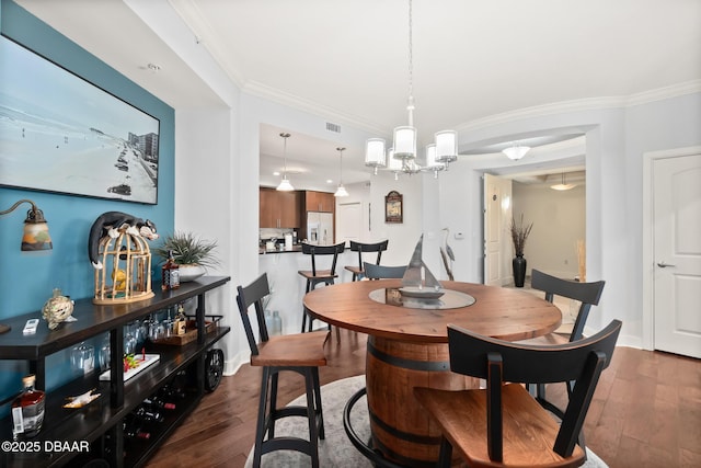 dining space with a notable chandelier, ornamental molding, and dark hardwood / wood-style floors