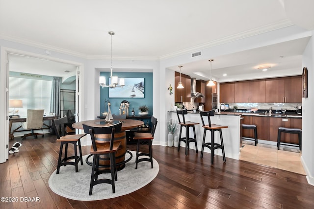 dining space featuring ornamental molding, dark hardwood / wood-style floors, sink, and a chandelier