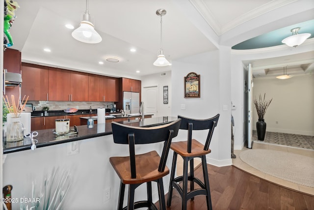 kitchen with pendant lighting, crown molding, stainless steel fridge, and tasteful backsplash