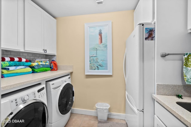 laundry room with light tile patterned floors, washer and clothes dryer, and cabinets