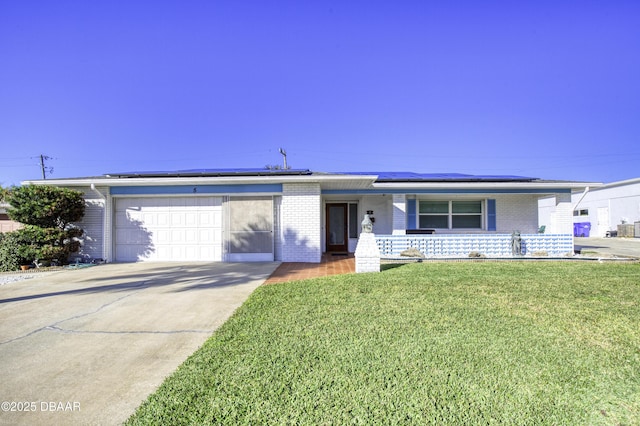 ranch-style house featuring a front lawn, solar panels, covered porch, and a garage