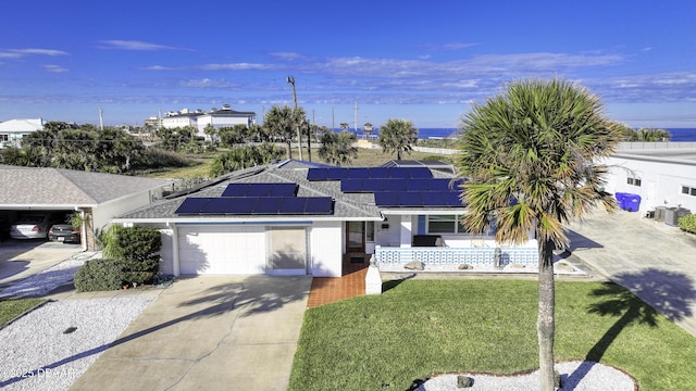 view of front of home with a garage, a front yard, and solar panels