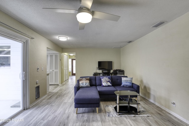 living room with ceiling fan, a textured ceiling, and light hardwood / wood-style flooring