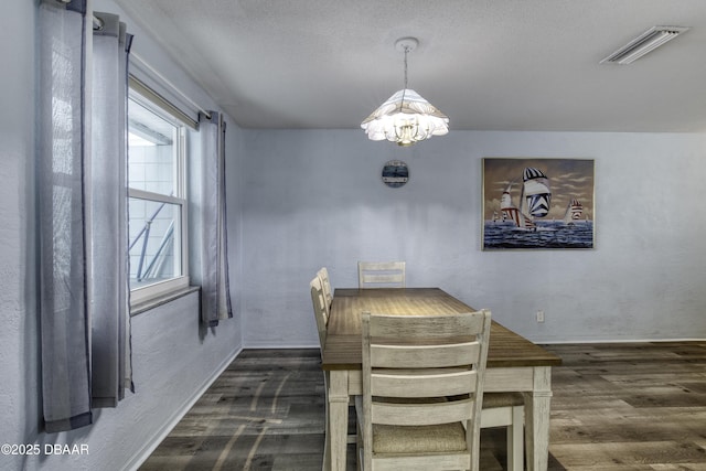 unfurnished dining area with a wealth of natural light, dark hardwood / wood-style floors, a textured ceiling, and an inviting chandelier