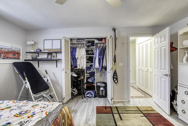 bedroom with light hardwood / wood-style floors, two closets, and a textured ceiling